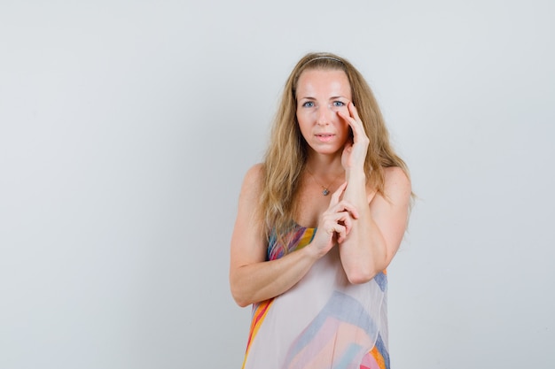 Young woman in summer dress touching face skin and looking pretty 