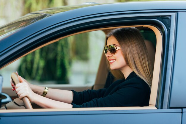 Молодая женщина в солнцезащитных очках за рулем