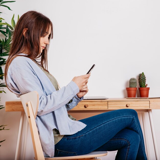 Young woman surfing smartphone at workspace