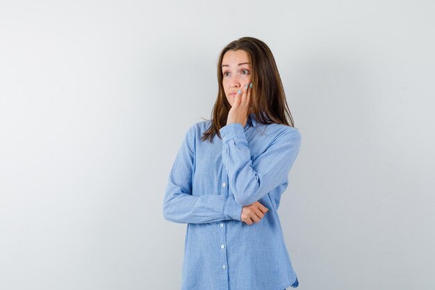 Young woman surprising and holding her hands on her cheeks on white background