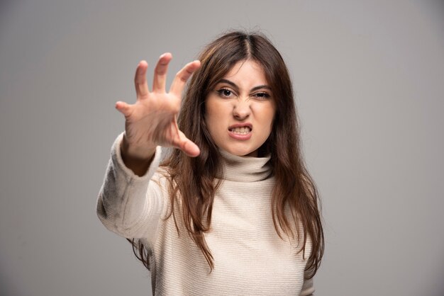 A young woman in sweater standing and showing claws .