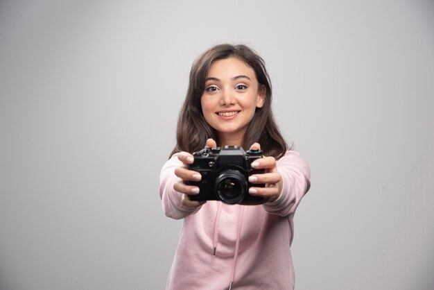 Young woman in sweatshirt showing her camera.