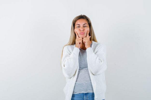 Free photo young woman in t-shirt, jacket keeping fingers on cheeks and looking gloomy , front view.