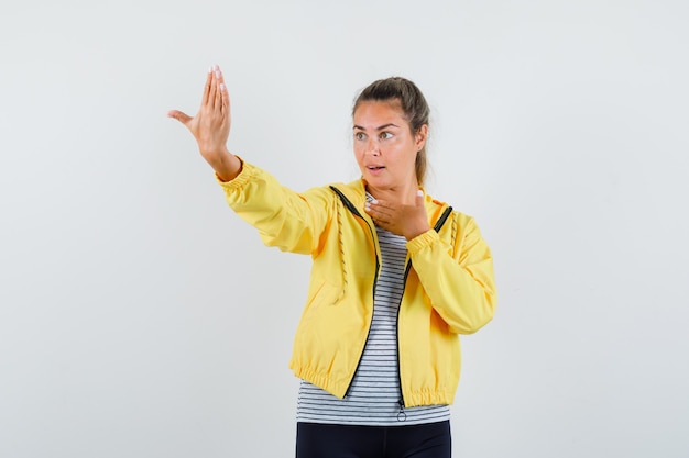 Young woman in t-shirt, jacket pretending to pose while taking selfie and looking elegant , front view.