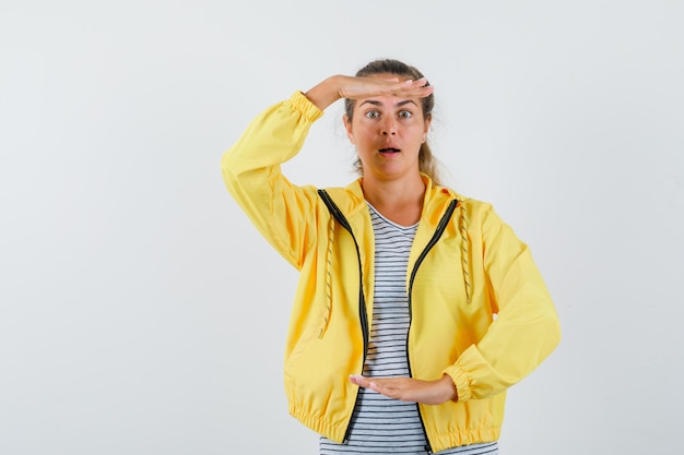 Free photo young woman in t-shirt, jacket showing large size sign and looking amazed , front view.