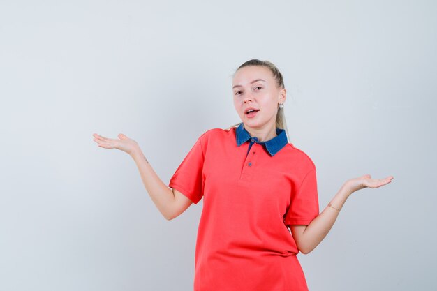 Young woman in t-shirt making scales gesture and looking confident