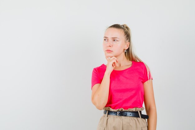 Young woman in t-shirt and pants looking away and looking thoughtful