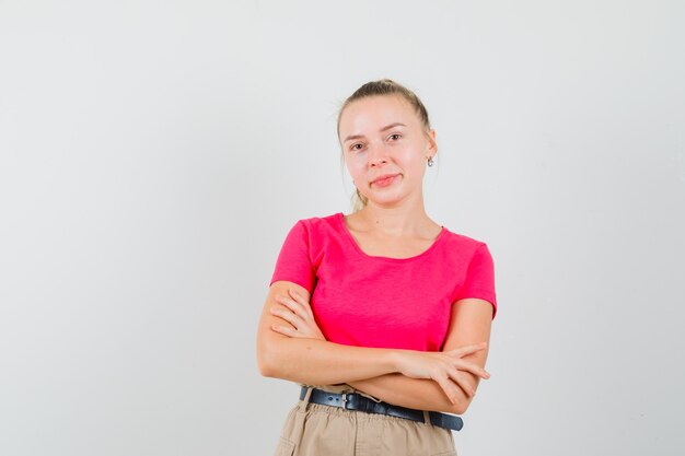 Young woman in t-shirt and pants standing with crossed arms and smiling