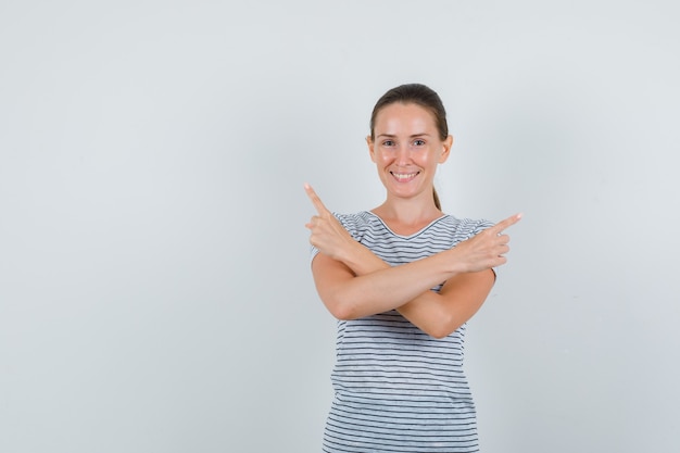 Young woman in t-shirt pointing to side and looking cheerful , front view.