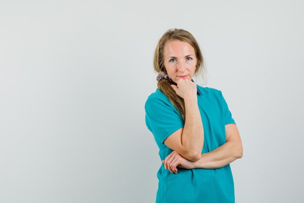 Young woman in t-shirt propping chin on fist and looking gentle 