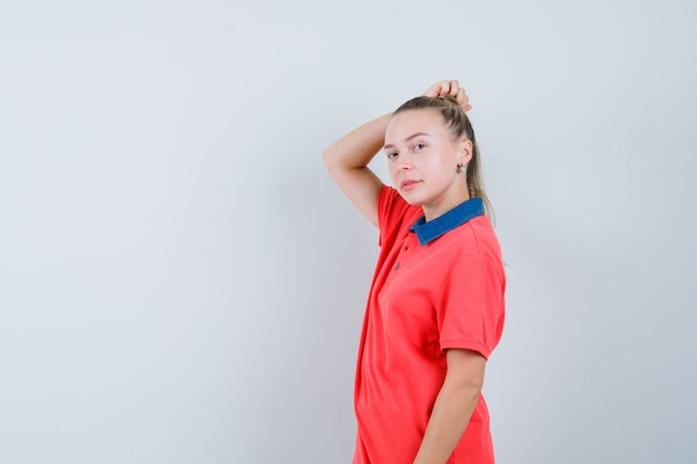 Young woman in t-shirt scratching head and looking confident