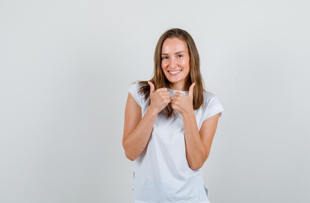Молодая женщина в футболке показывает палец вверх и выглядит счастливой