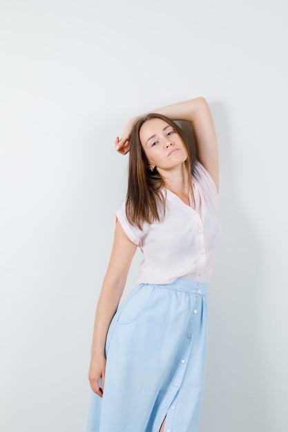 Young woman in t-shirt, skirt posing while standing and looking fascinating , front view.