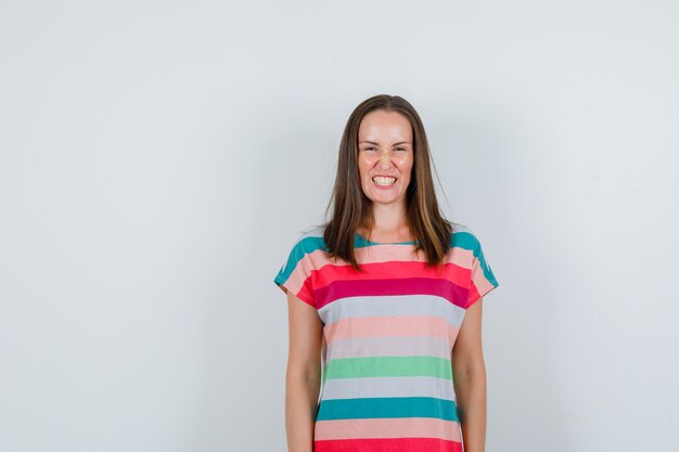 Young woman in t-shirt smiling with clenched teeth , front view.