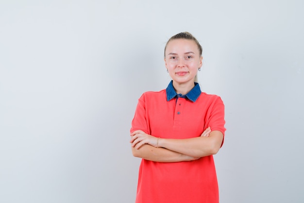 Free photo young woman in t-shirt standing with crossed arms and looking jolly