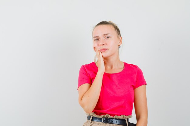 歯痛に苦しんでいて、不快に見えるTシャツの若い女性