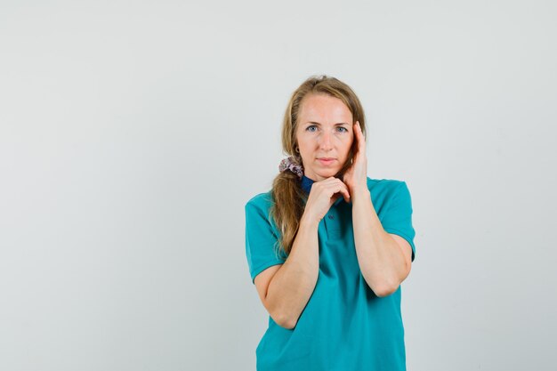 Young woman in t-shirt touching her face skin and looking delicate 