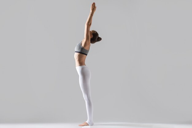 Young woman in Tadasana pose, grey studio background