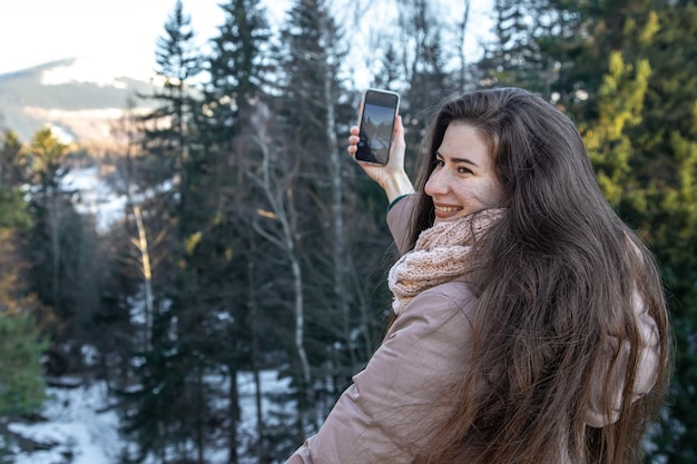 若い女性がスマートフォンで山の写真を撮る