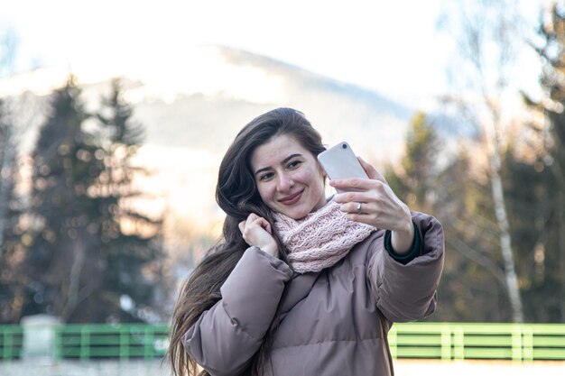 Free photo a young woman takes a selfie on a walk in the mountains