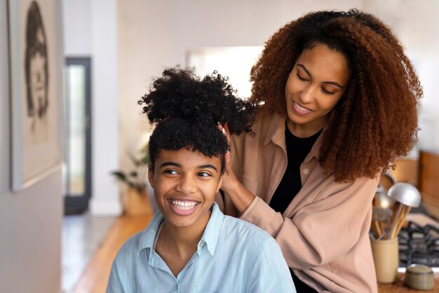 男の子のアフロヘアーの世話をする若い女性