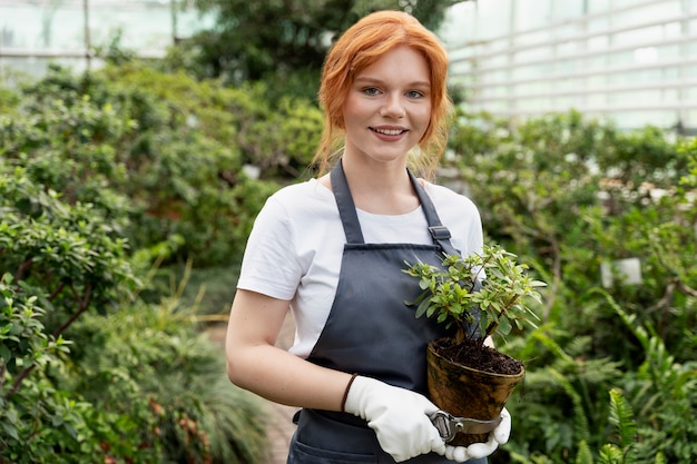 温室で彼女の植物の世話をしている若い女性