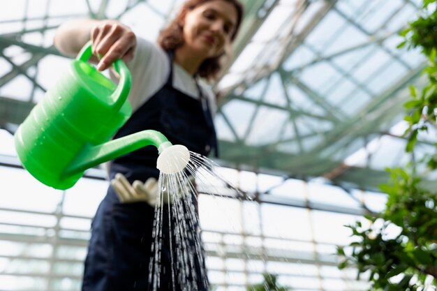 温室で彼女の植物の世話をしている若い女性