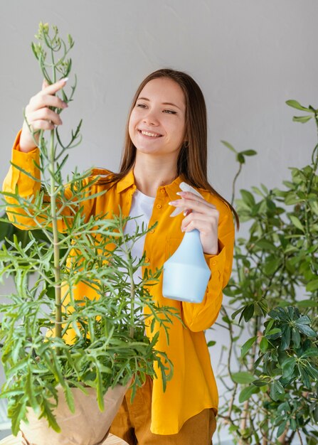 집에서 그녀의 식물을 돌보는 젊은 여자