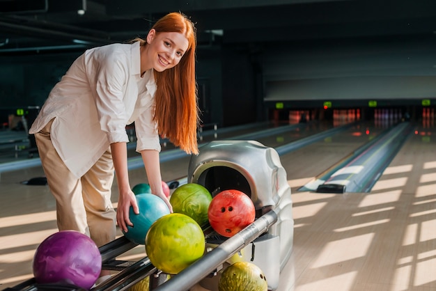 Giovane donna che prende una palla da bowling variopinta