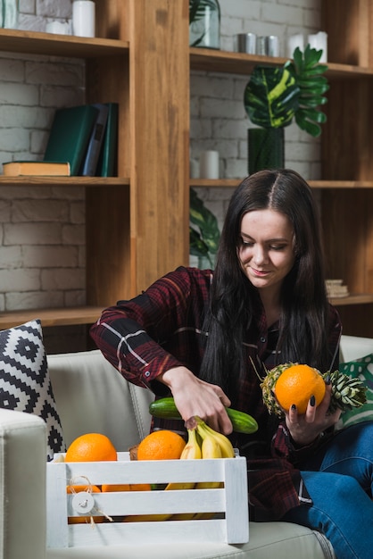 Free photo young woman taking fruits and vegetables from parcel