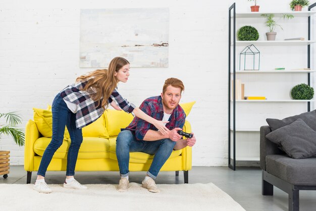Молодая женщина, принимая джойстик от своего парня, играя в видеоигру