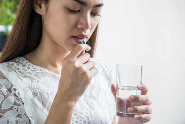 Free photo young woman taking medicine pill after doctor order