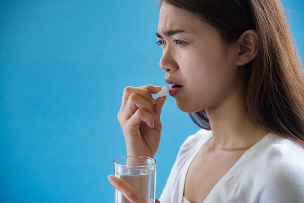 Young woman taking medicine pill after doctor order