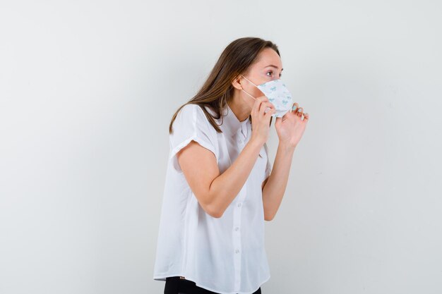 Young woman taking off her medical mask