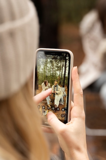 Young woman taking photo of her friends using her smartphone