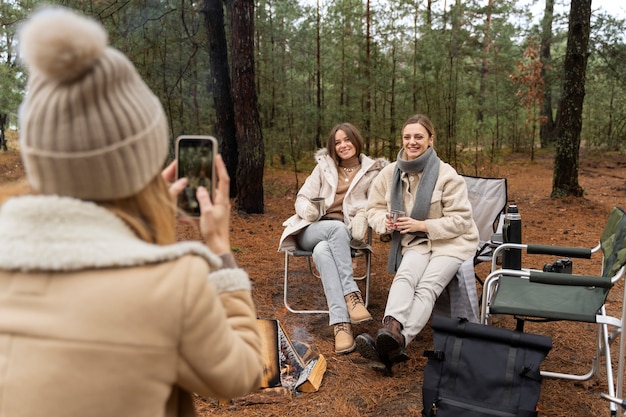 Foto gratuita giovane donna che scatta foto dei suoi amici usando il suo smartphone