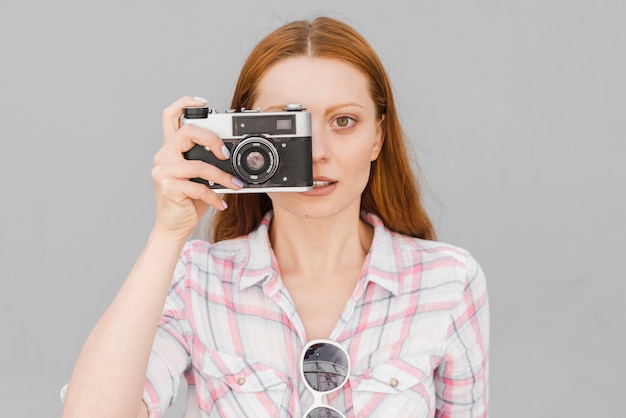 Young woman taking photo with camera in studio