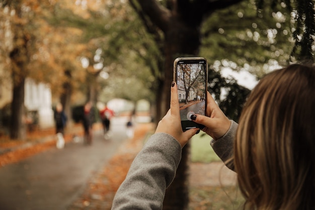 Молодая женщина фотографирует с помощью смартфона