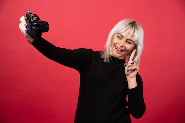 Young woman taking pictures witha camera on a red background. High quality photo