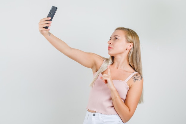 一重項で指でselfieを取る若い女性