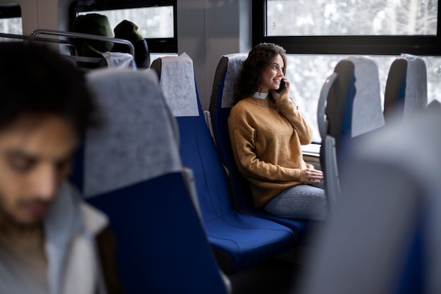 Молодая женщина разговаривает по смартфону во время поездки на поезде