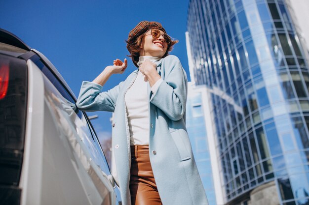 Young woman talking on the phone by electro car in the center