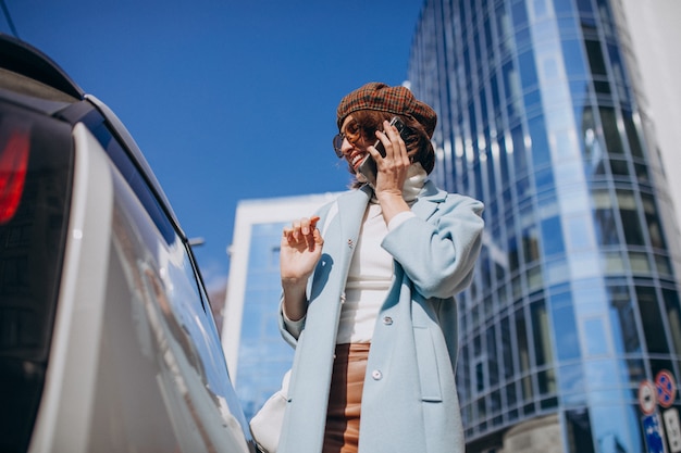 Young woman talking on the phone by electro car in the center