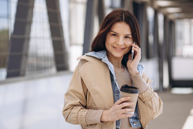 電話で話し、コーヒーを飲む若い女性