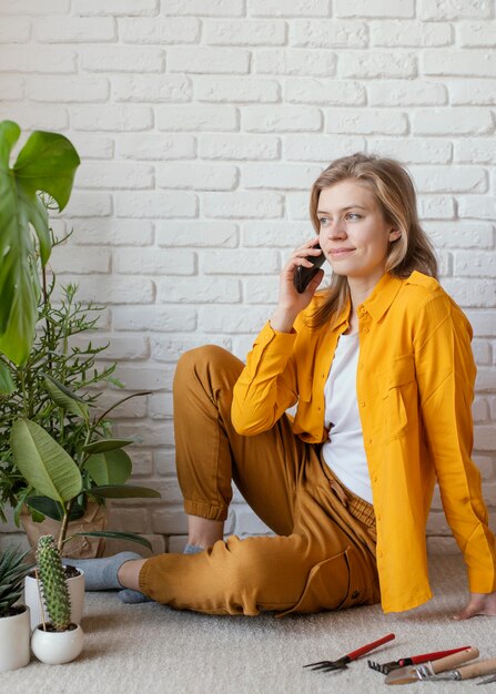 Young woman talking on the phone next to her plant