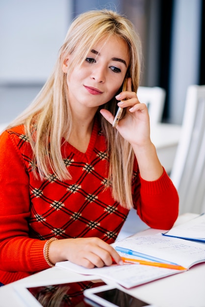 Young woman talking on phone at table