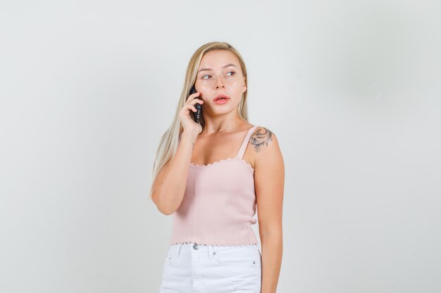 Young woman talking on phone while looking aside in singlet