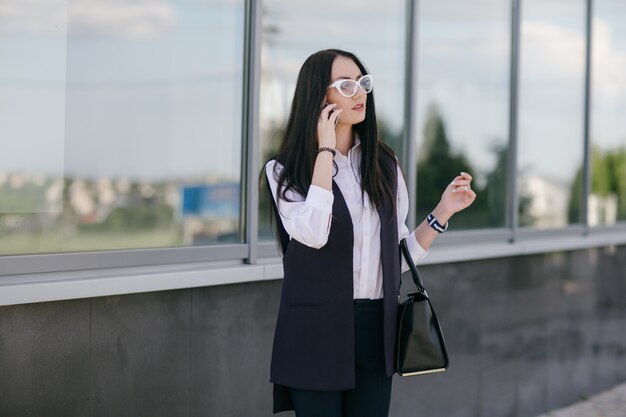 Young woman talking on a phone with a black bag