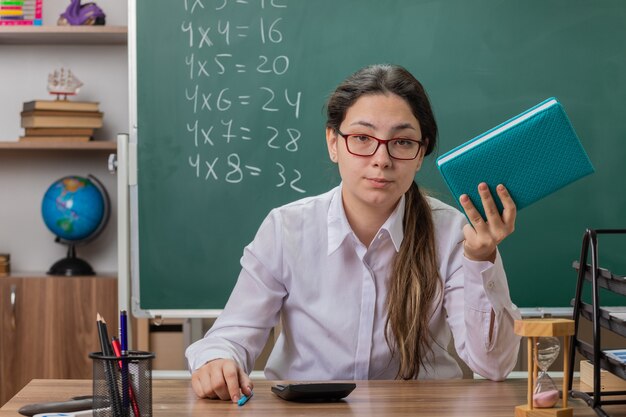 Young woman teacher wearing glasses holding notebook