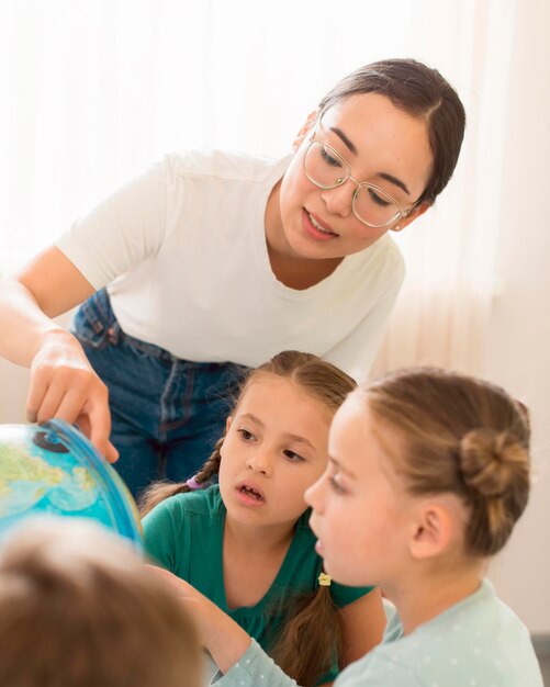 Молодая женщина преподает географию детям